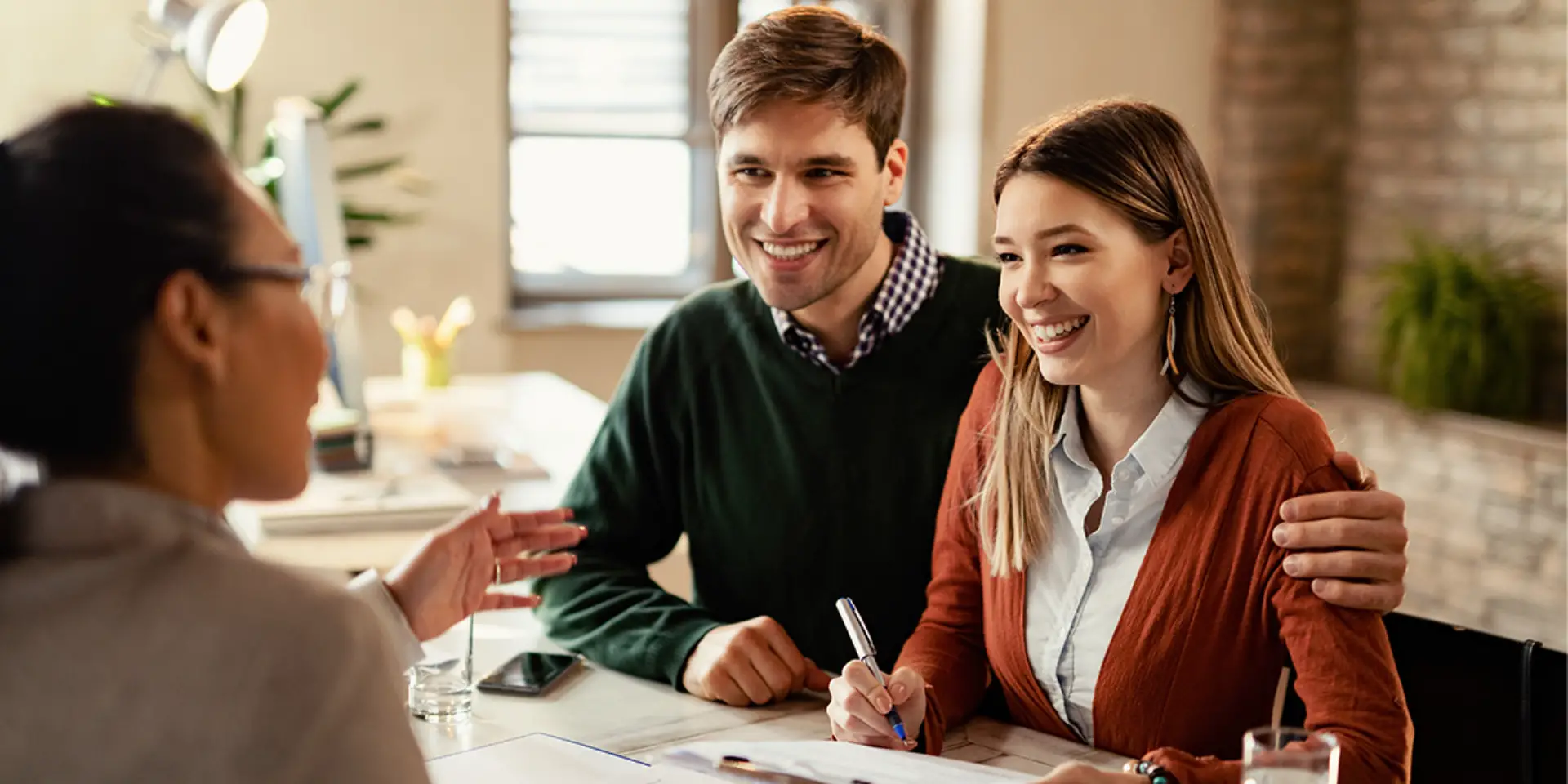 young-happy-couple-signing-contract-while-being-meeting-with-insurance-agent-office